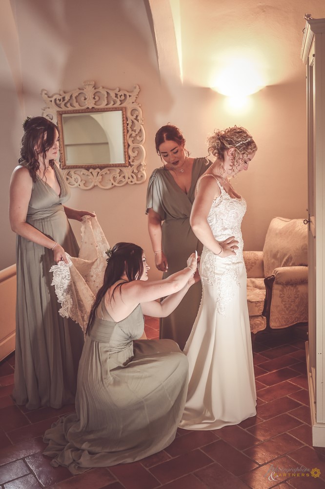 The bridesmaids help the bride with the dress.